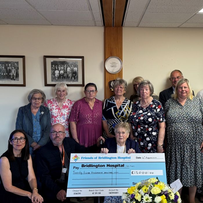 A group of people smiling with a giant cheque