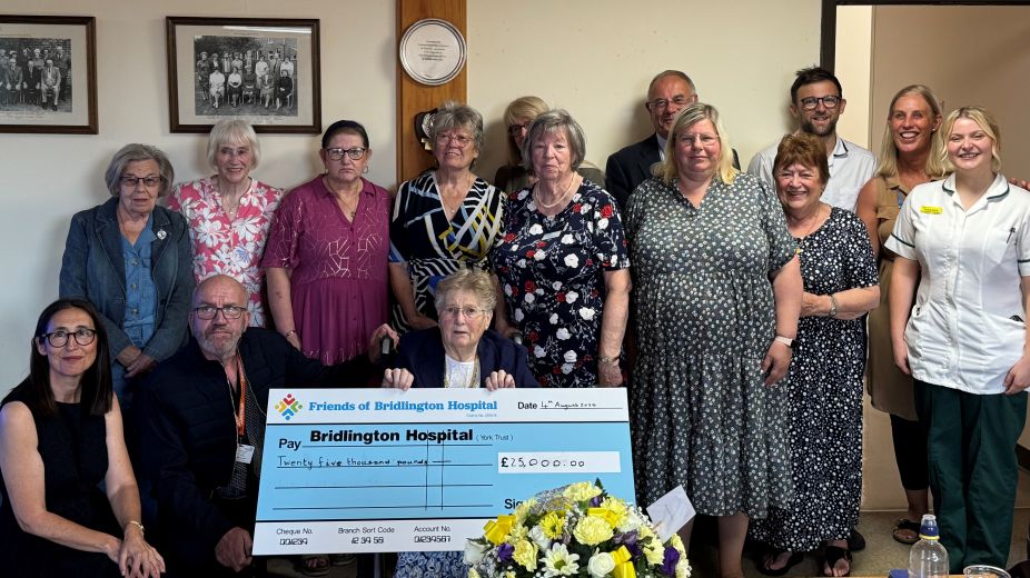 A group of people smiling with a giant cheque