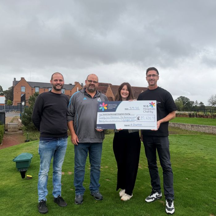 4 people standing on a golf course with a giant cheque