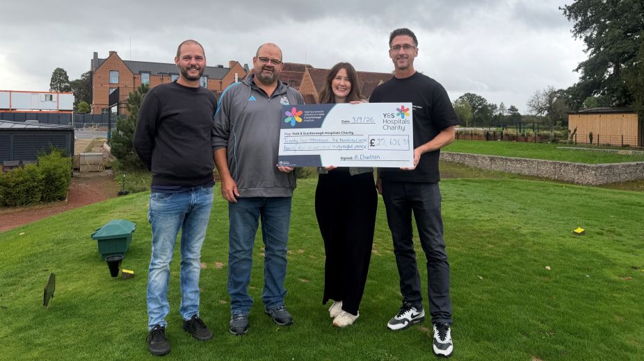 4 people standing on a golf course with a giant cheque