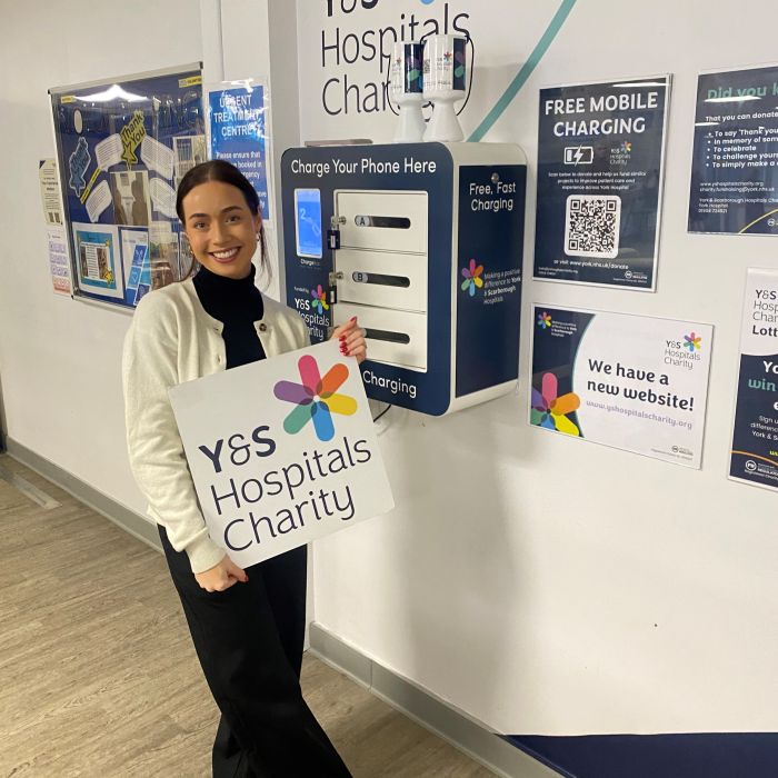 Supporter smiling with charity logo board sign