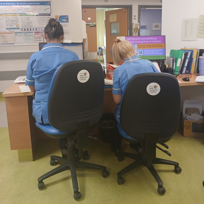 2 nurses sitting and working at a desk on new office chairs 