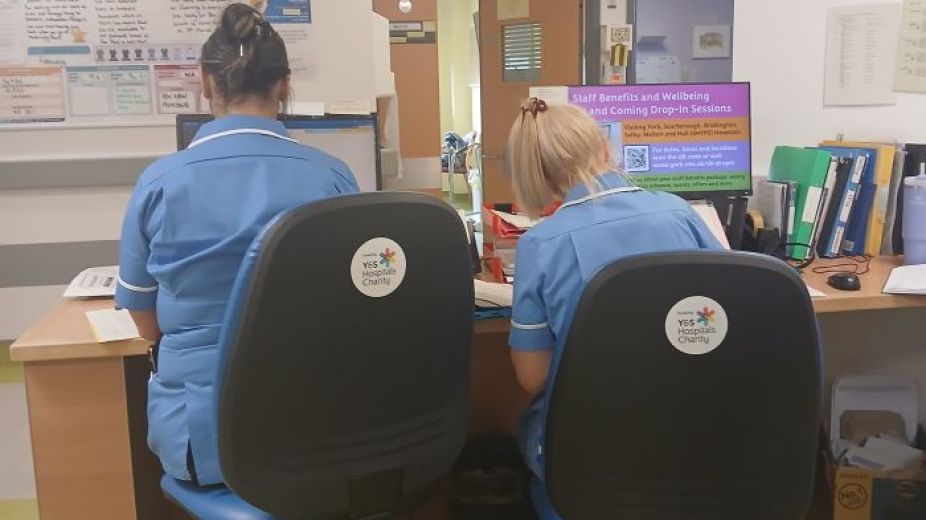 2 nurses sitting and working at a desk on new office chairs 