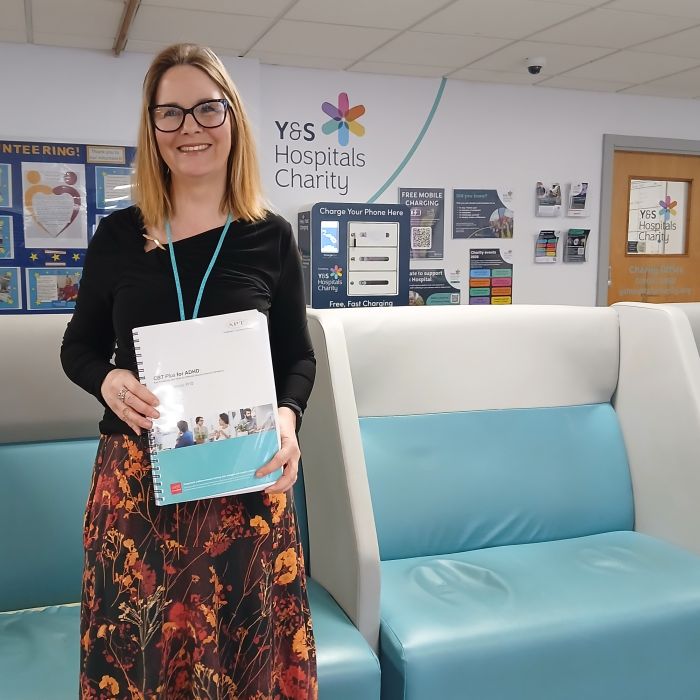 nurse holding course material by the Charity office