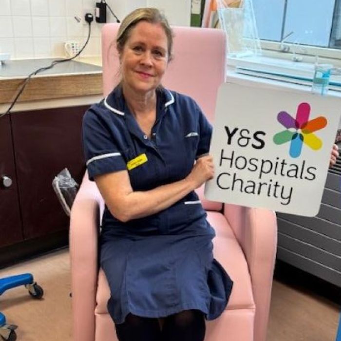 Lady sitting on new reclining chair with charity logo sign