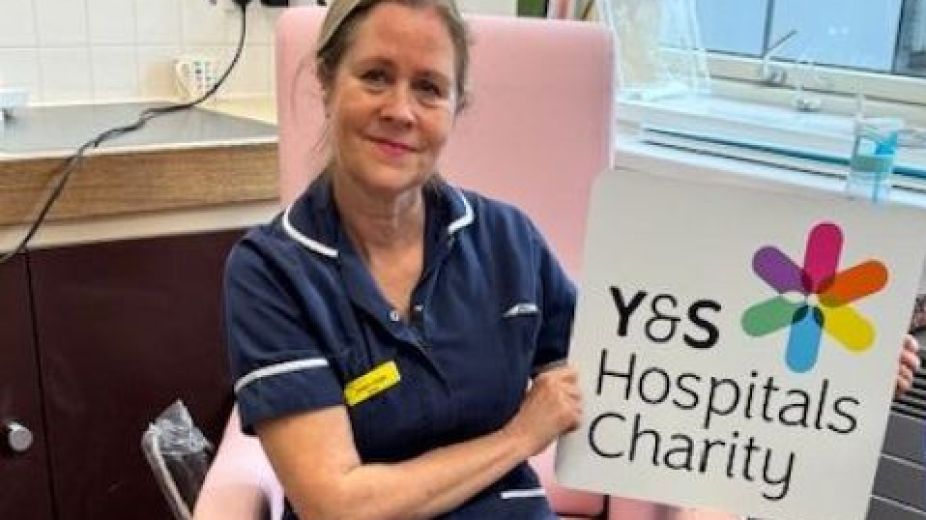 Lady sitting on new reclining chair with charity logo sign