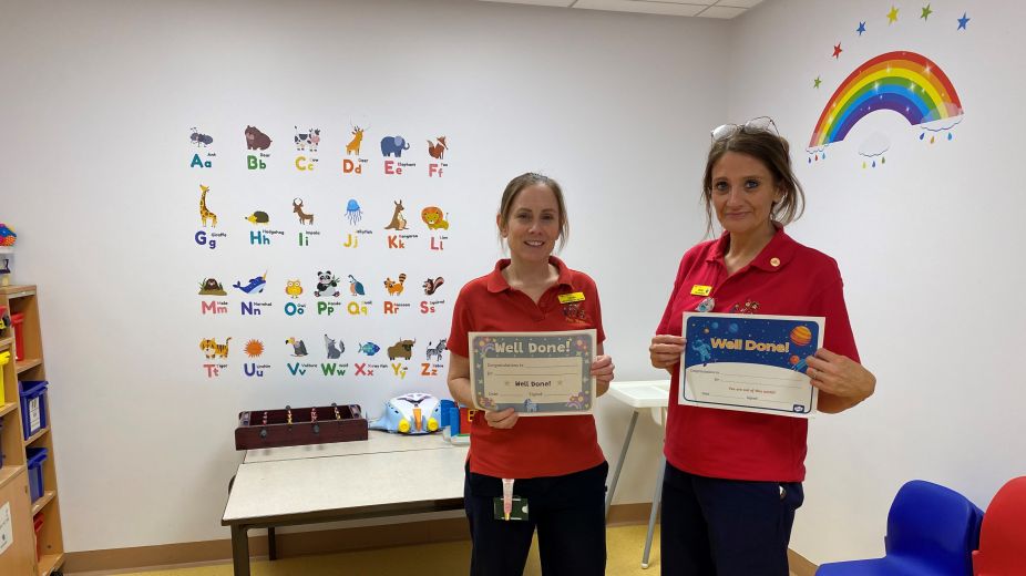 2 ladies holding children certificates