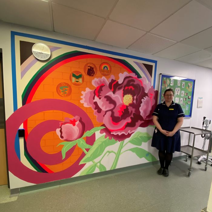 nurse in uniform stood by colourful wall murial