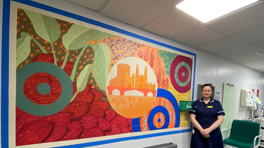 nurse in uniform stood by colourful wall murial
